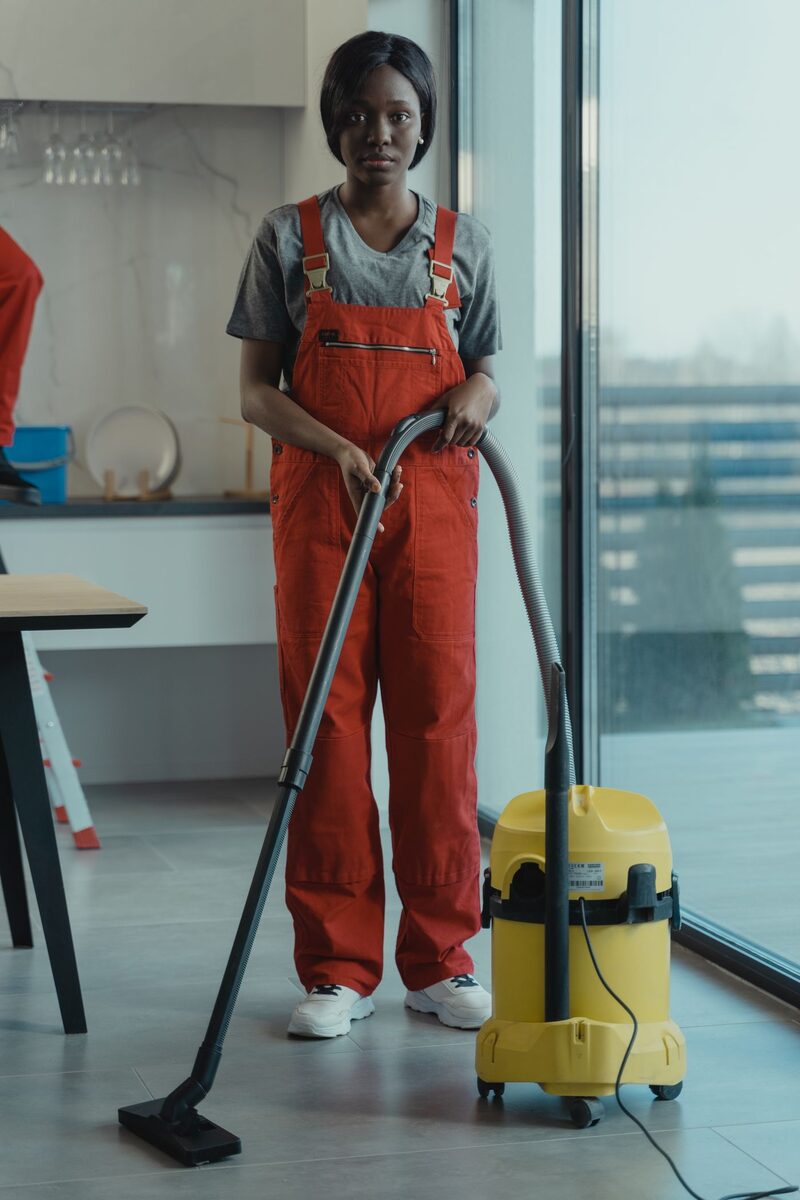 Cleaner vacuuming the carpet of a lived-in apartment
