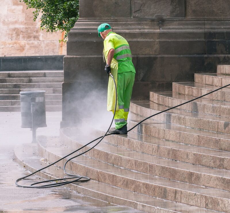 Worker pressure washing a stone stairway